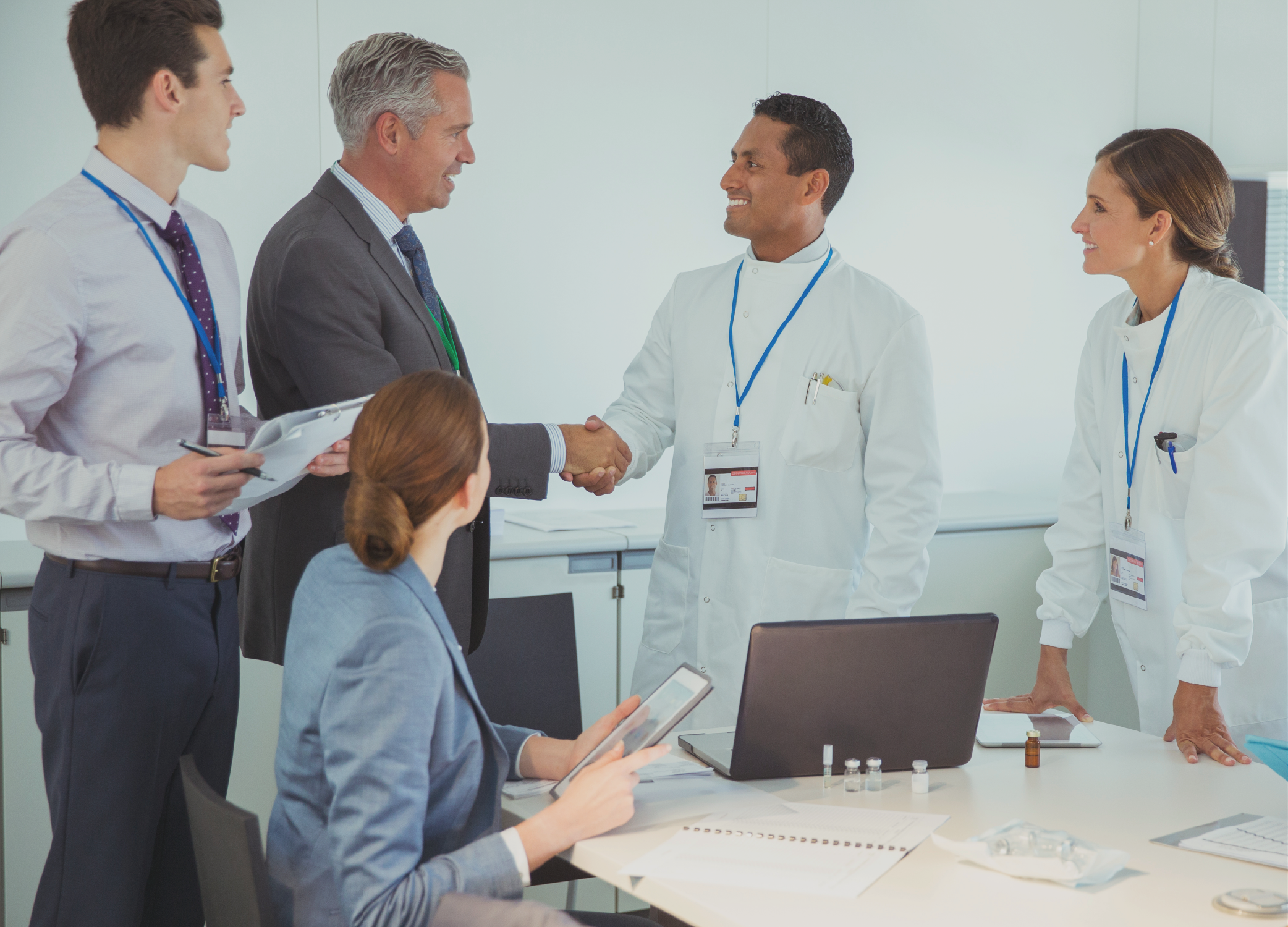 Five people, two of them dressed in white coats, meeting around a table.