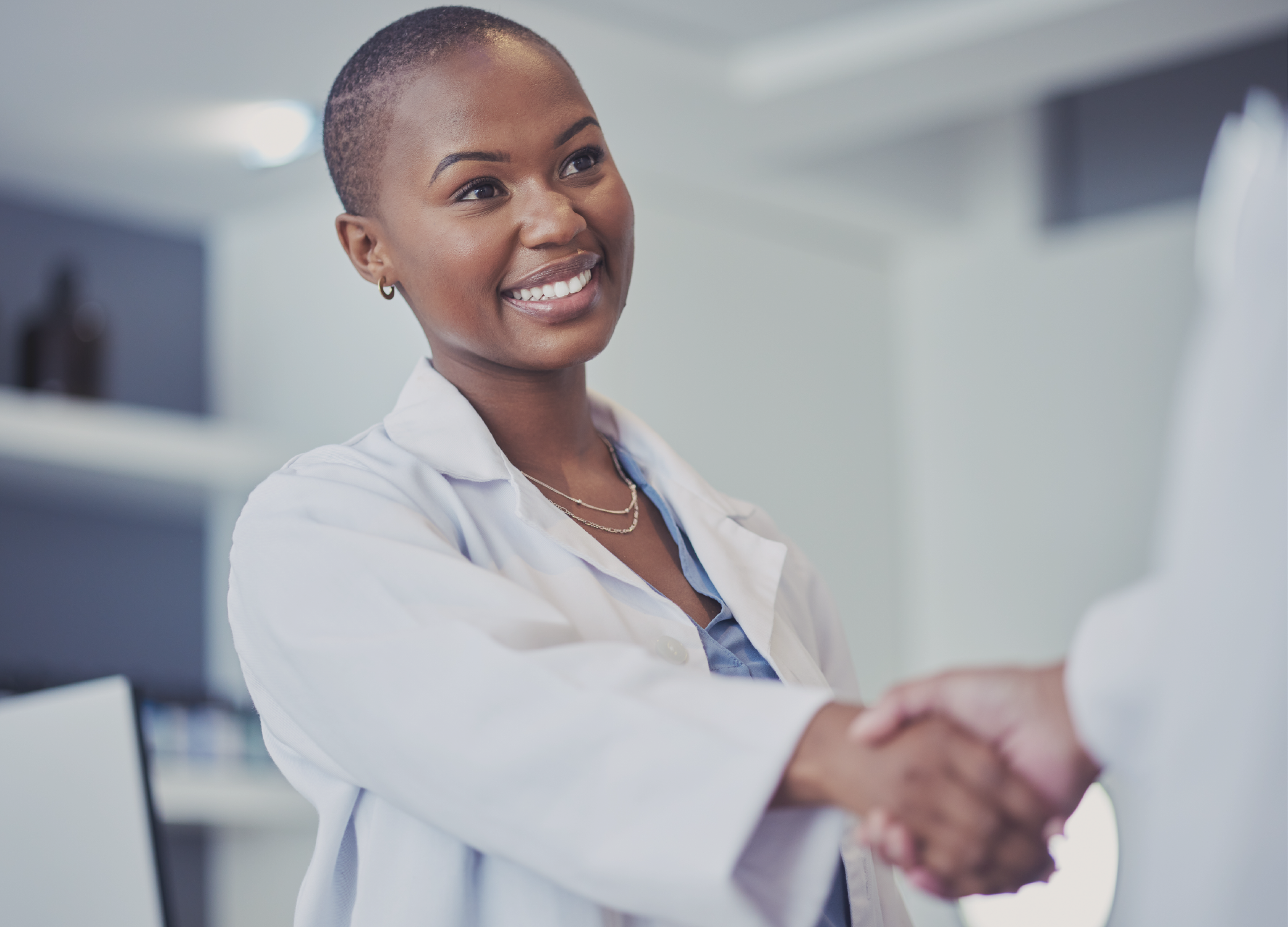 A woman lab technician as part of a clinical trial shaking hands with someone.