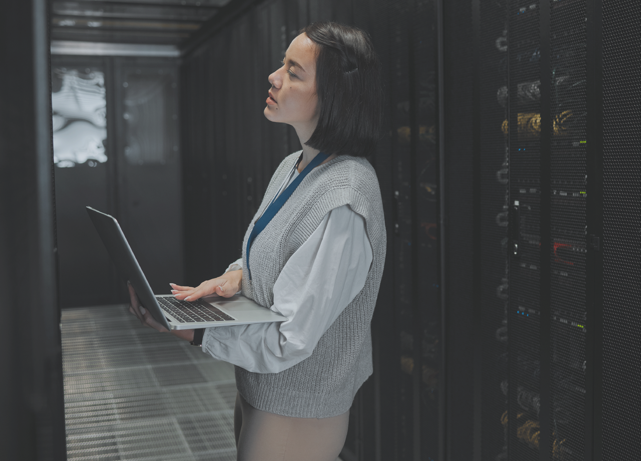 An IT technician in a data and server center holding a laptop.
