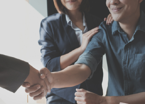 A man shaking hands with someone else and all parties smiling.