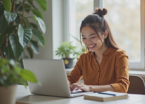 Female employee smiling and typing on a laptop keyboard.