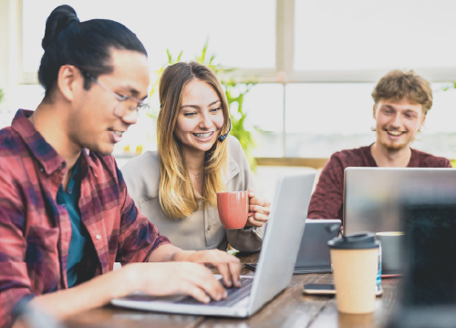 Three employees, two men and one woman, collaborating around a table.