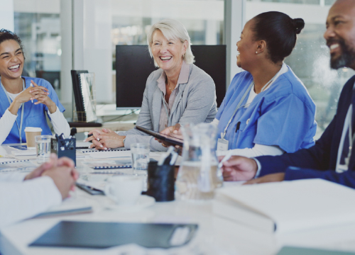 Four healthcare employees around a table smiling and laughing.
