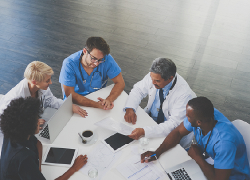 Five healthcare employees having a conference around a table.