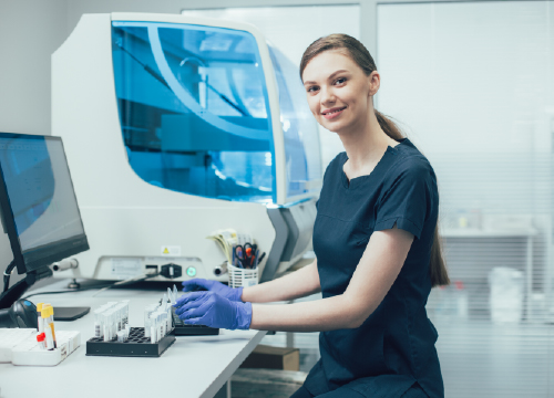 Life sciences nurse working at a counter wearing gloves with test tubes.