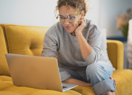 Remote worker sitting on her sofa working on a laptop.