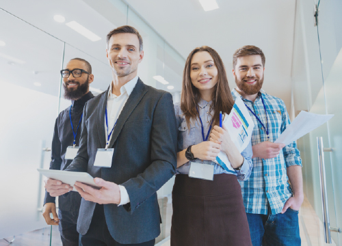 Four employees smiling and walking down a hallway together.