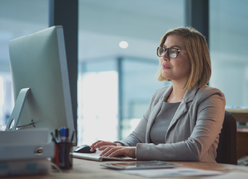 Access One image with a woman wearing glasses in front of a computer monitor.