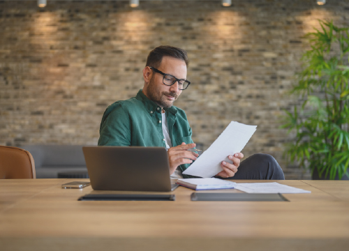 Certification Assistant photo of a man at a desk with papers in front of him.