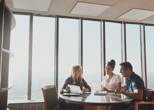 Three people in a conference room discussing policies for PolicyPro