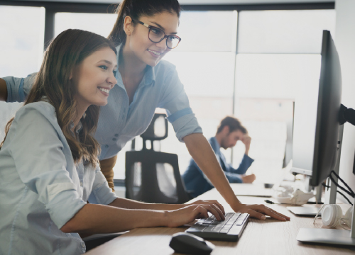 Sourcepass image with two women looking at a flatscreen computer monitor.